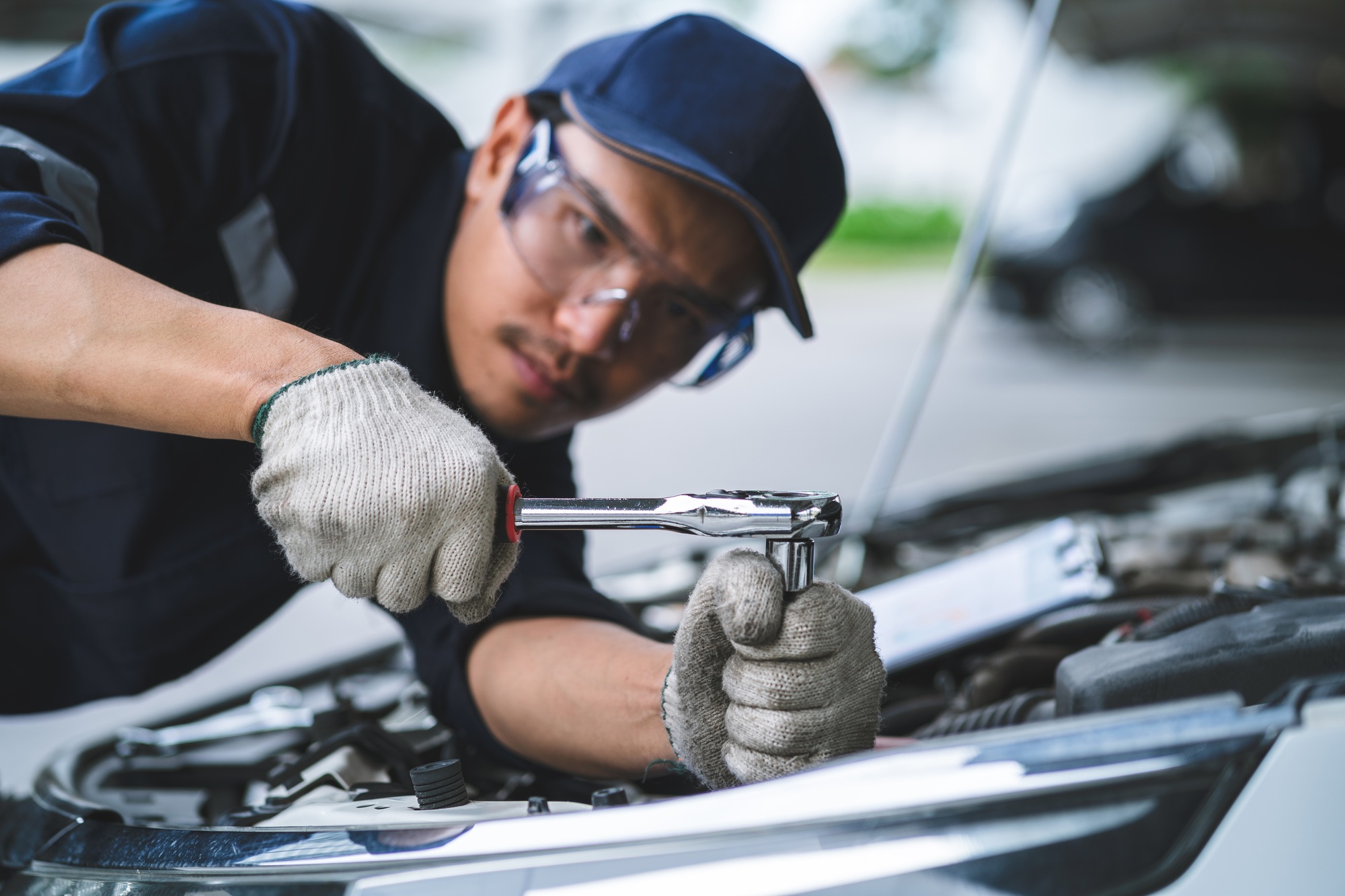 A man is working on a car engine with a wrench.
